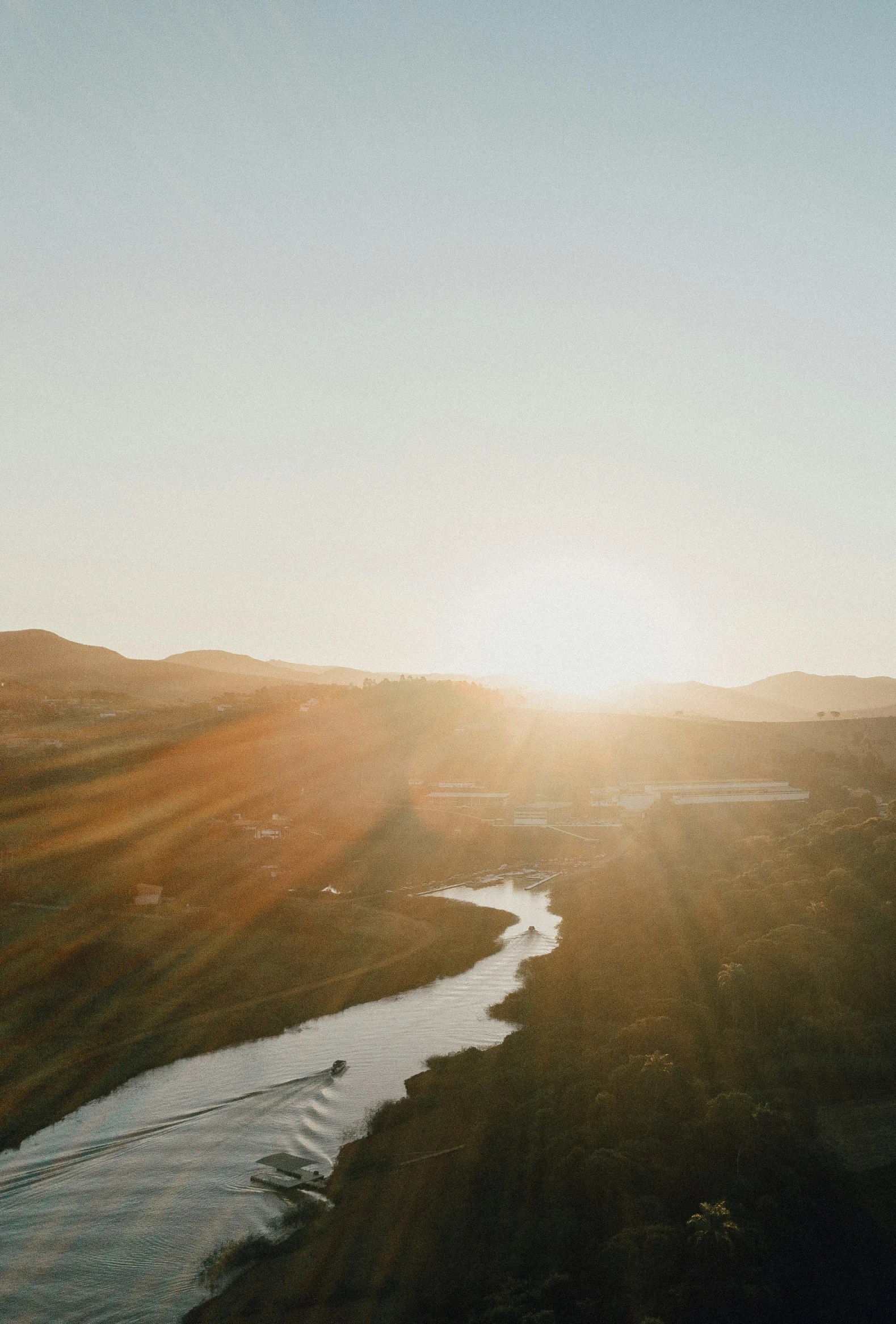 the sun sets over a river with land and trees