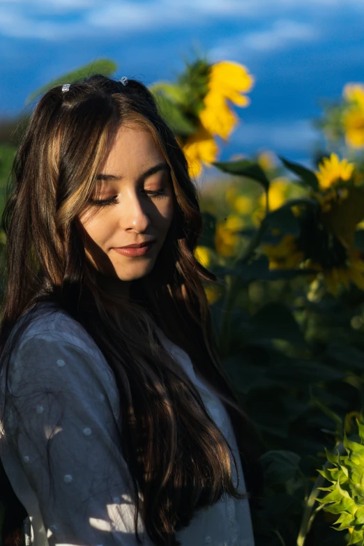 a beautiful young lady standing in front of a sunflower