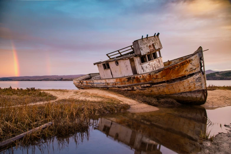 the boat is still in the water and is near a sandy beach