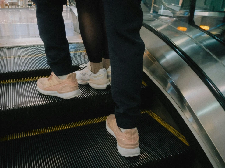 the person in sneakers is riding an escalator