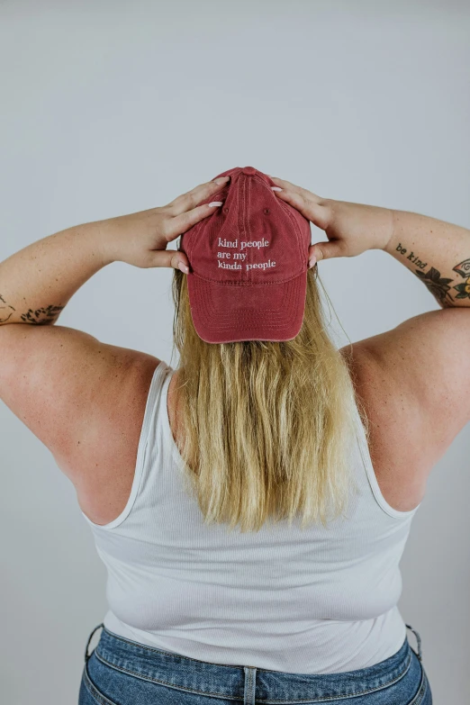a blonde woman with tattoos wearing a red hat