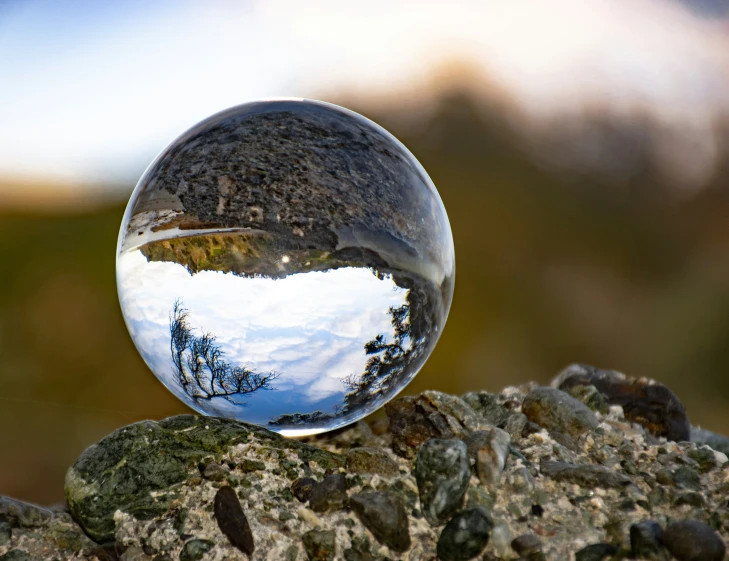 a clear glass ball sits on top of rocks