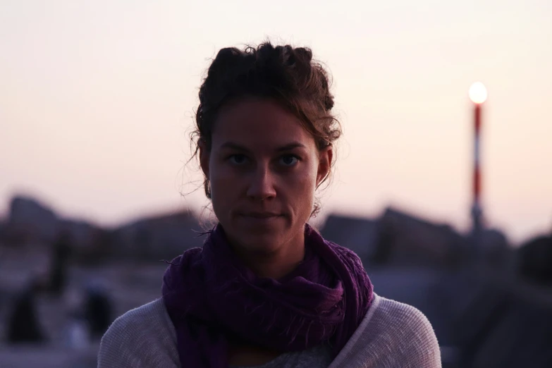 a woman with a scarf in front of a sunset