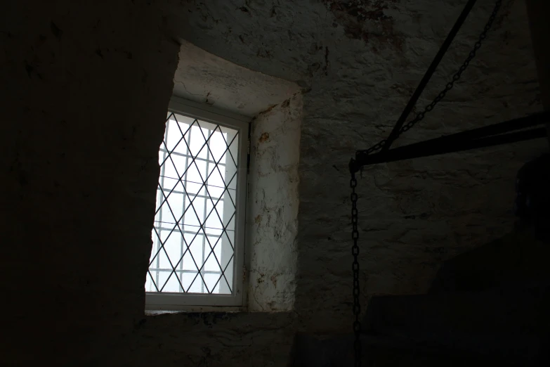 a small window near a wall with a chain hanging by it