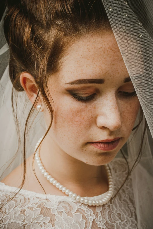 a young woman is wearing her wedding veil as she looks down