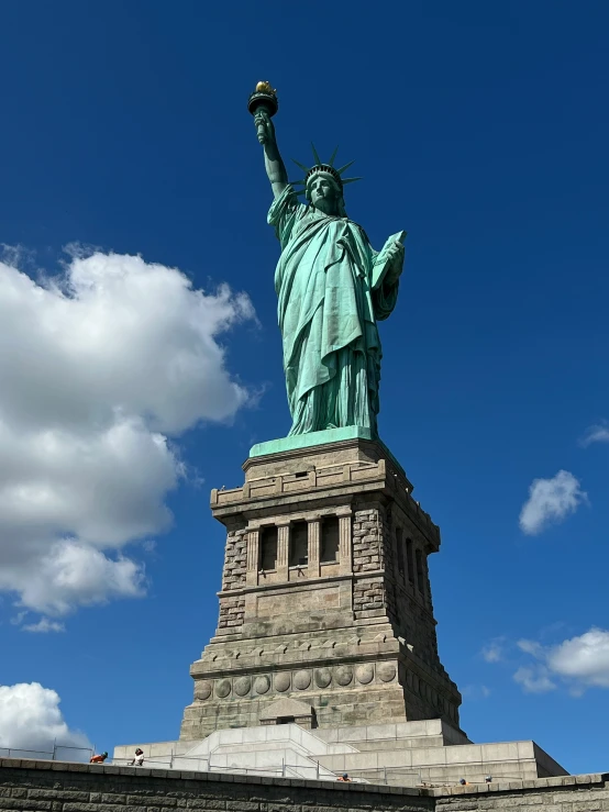 the statue of liberty is shown against a blue sky with clouds