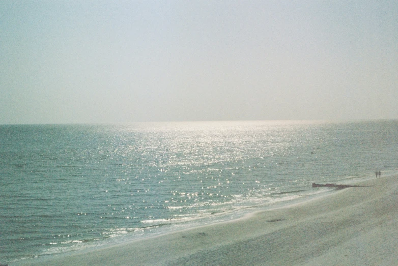 a view of a beach from a distance, with waves and a man walking in the water