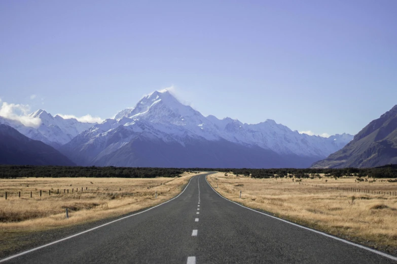 long stretch highway leading to snowy mountain range