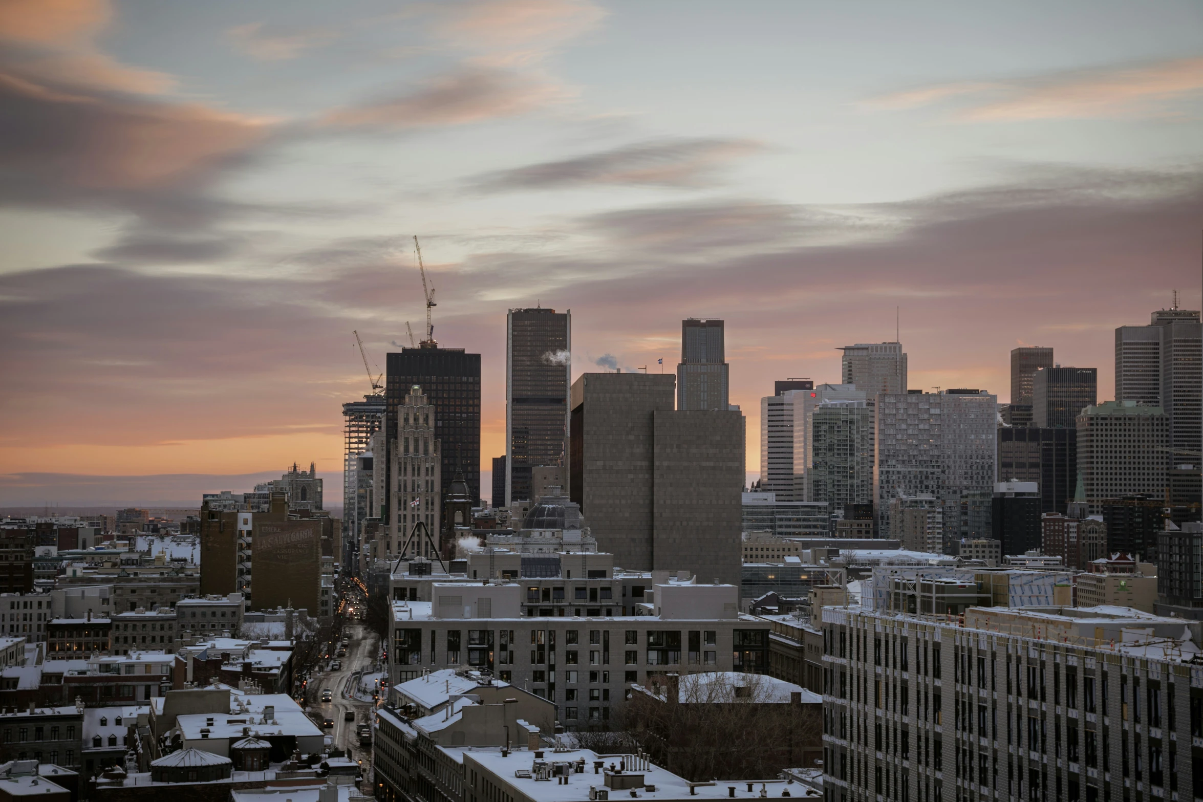 a view of a very tall city with snow on the roofs