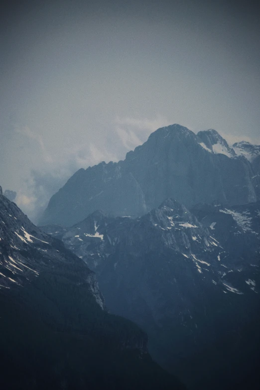 a flock of birds sitting on top of a mountain under cloudy skies