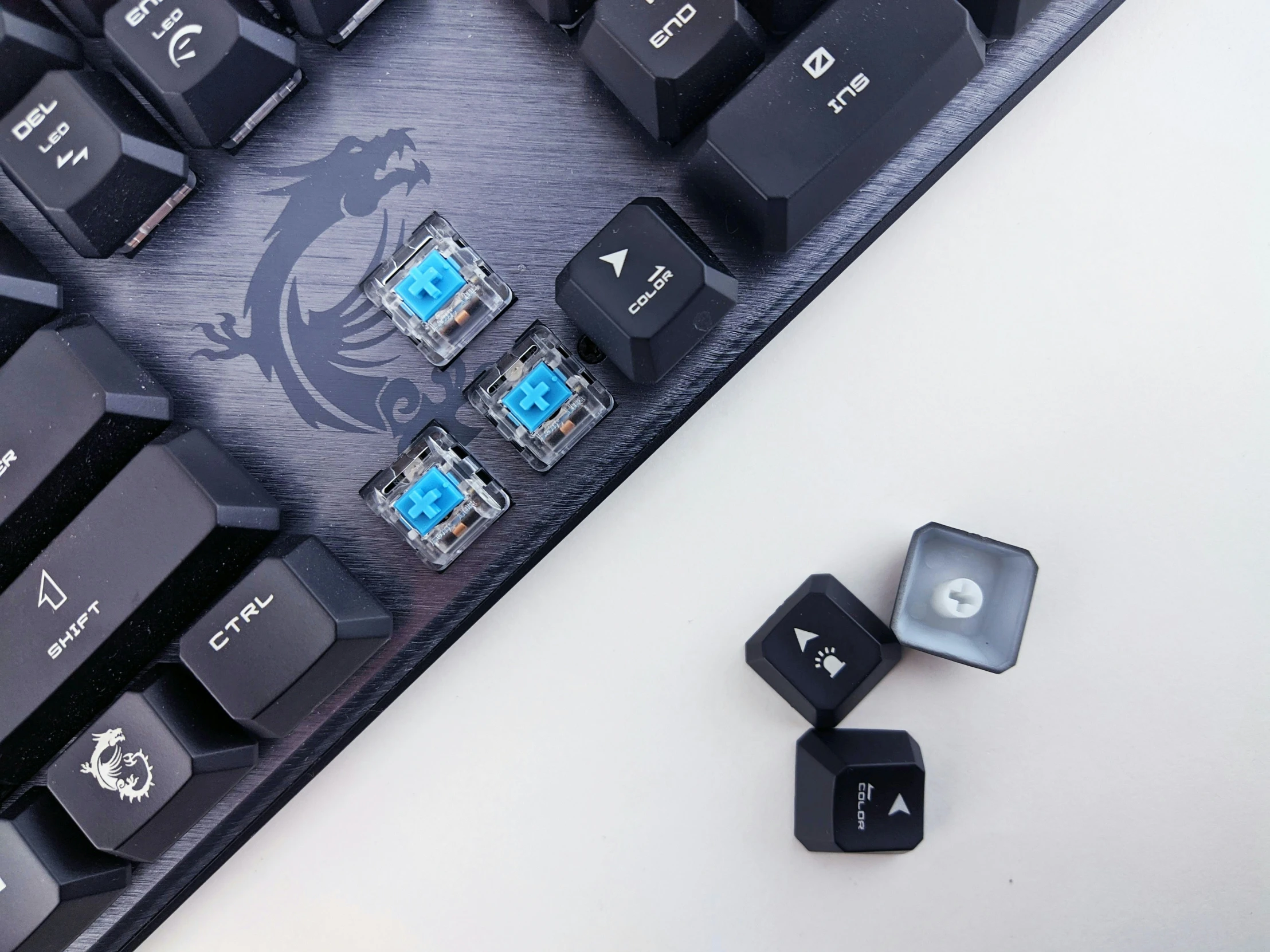 a keyboard and three smaller keycaps on a table