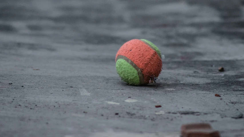a ball laying on the ground in the rain