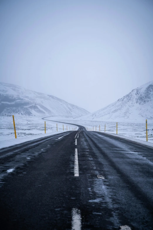 a snowy road with the sun shining through the fog