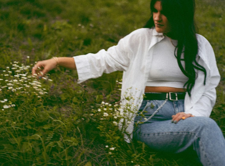 a young woman sits in a field of wildflowers