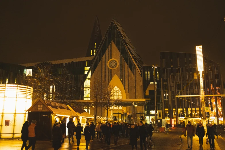 an outdoor night market with people walking and some buildings