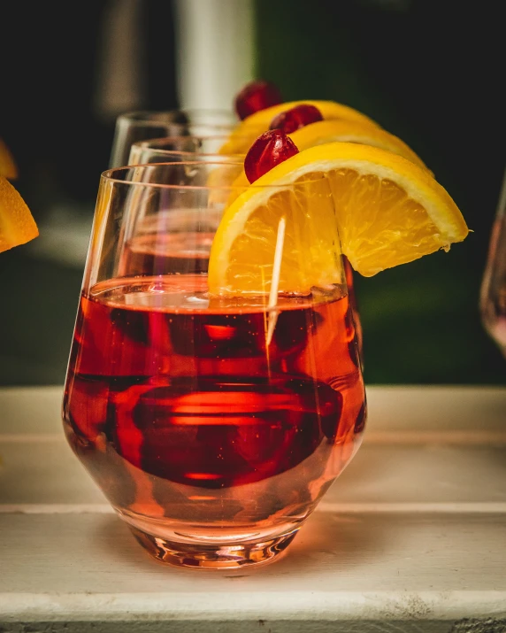 a wine glass filled with red liquid surrounded by slices of lemon