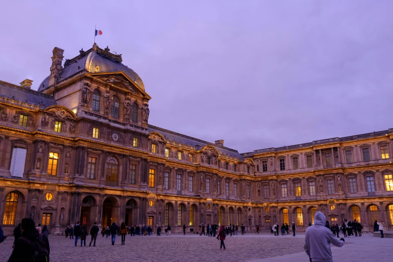 a courtyard has people walking around and lights are on