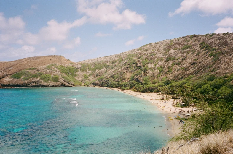 a boat is in a blue green ocean next to a sandy beach