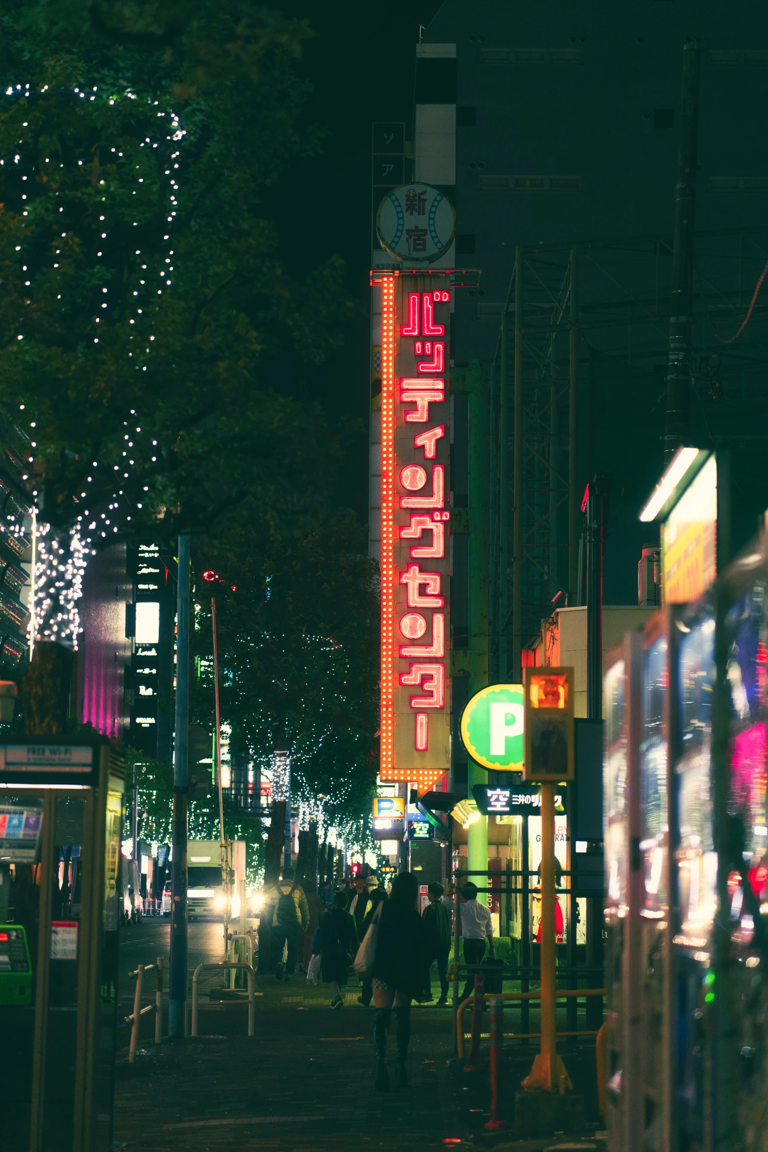 people walking down a street at night in the evening