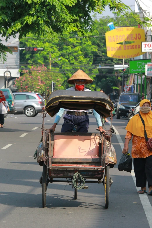a woman in a yellow hat is pulling a rickshaw