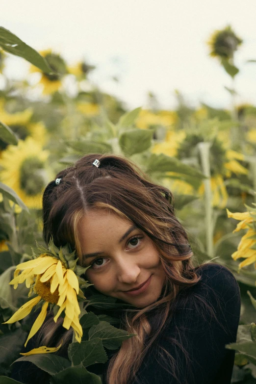 a woman standing in a field holding a sunflower