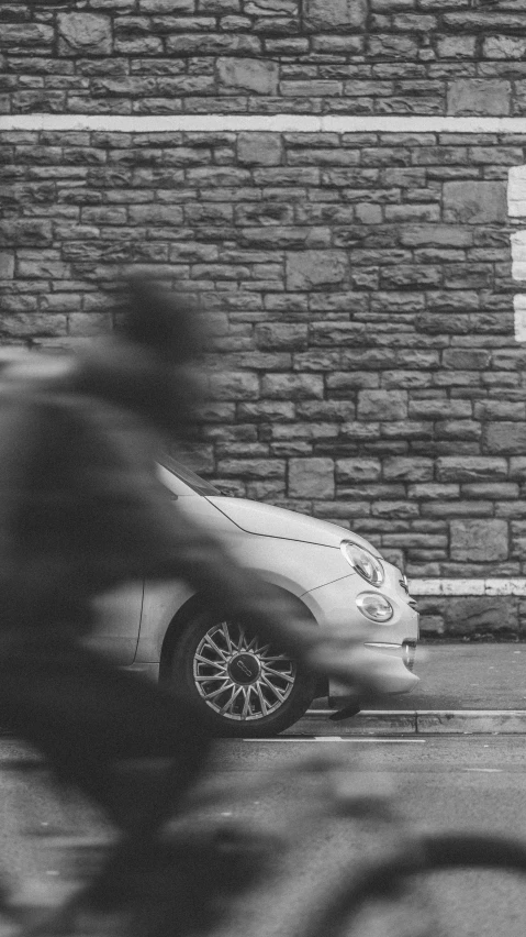 a man on a bike rides by a car