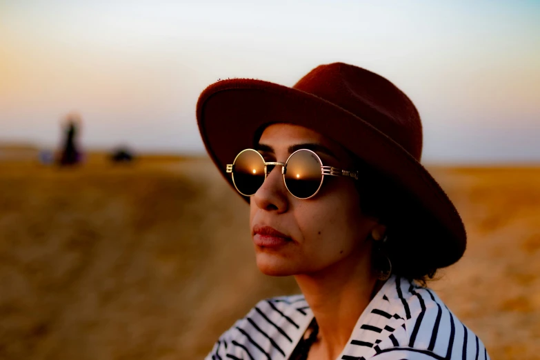 there is a woman wearing sunglasses and a hat on the beach