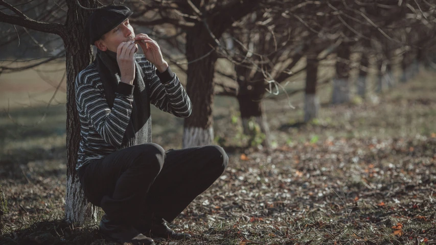 man in hat leaning against tree with one hand