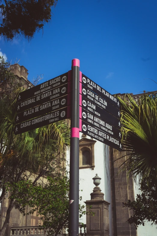 some signs near a large white building and trees