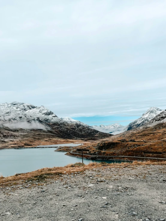 a lake surrounded by mountains under cloudy skies