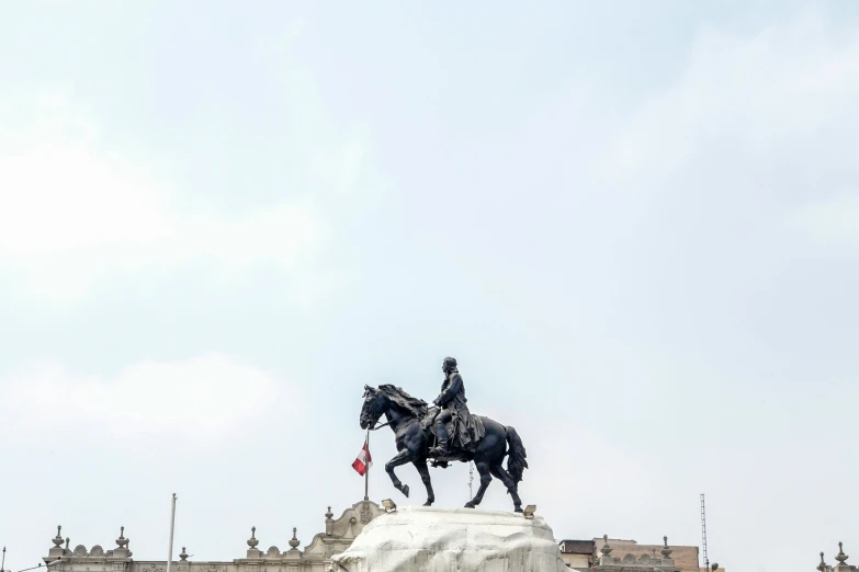 two statues of horses, two people on one, and a building with towers