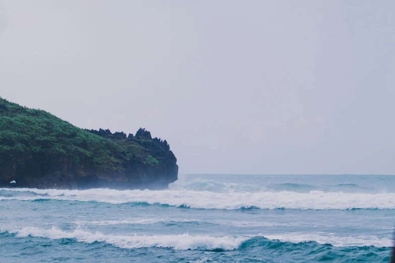 waves crash against an island on the ocean