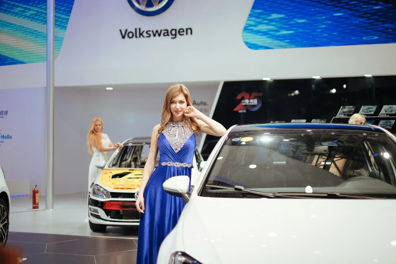 a woman posing next to several cars on display