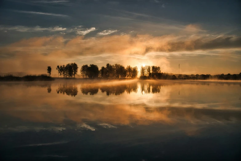 a lake is surrounded by forest at sunrise