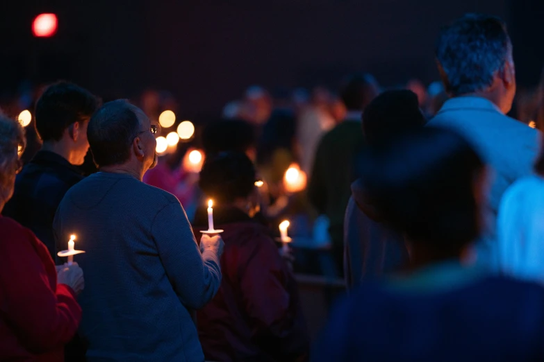 a large crowd standing next to each other holding candles in their hands