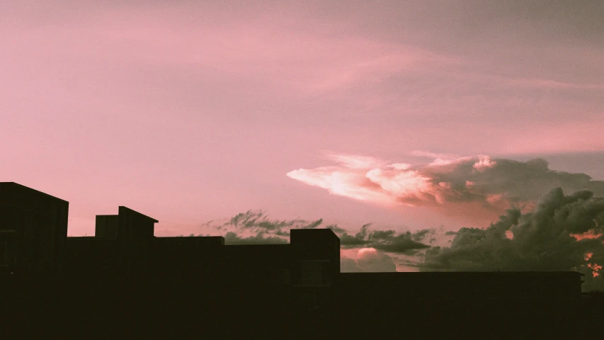 dark red clouds are in the sky as silhouettes of buildings