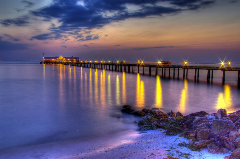 an ocean scene with pier lights reflecting off the water