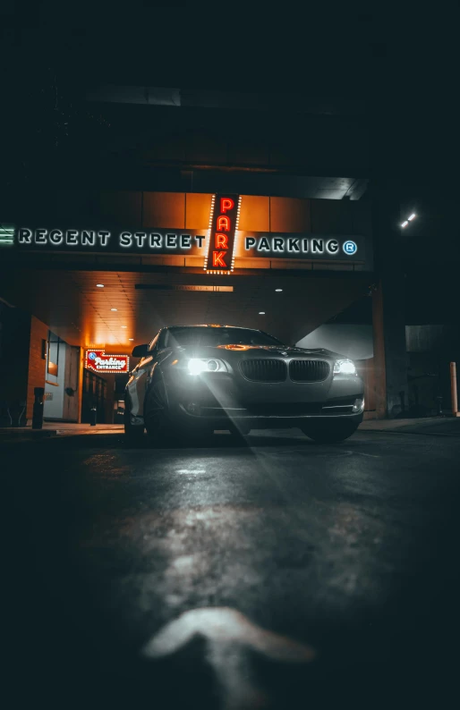 black car parked in front of an illuminated parking garage