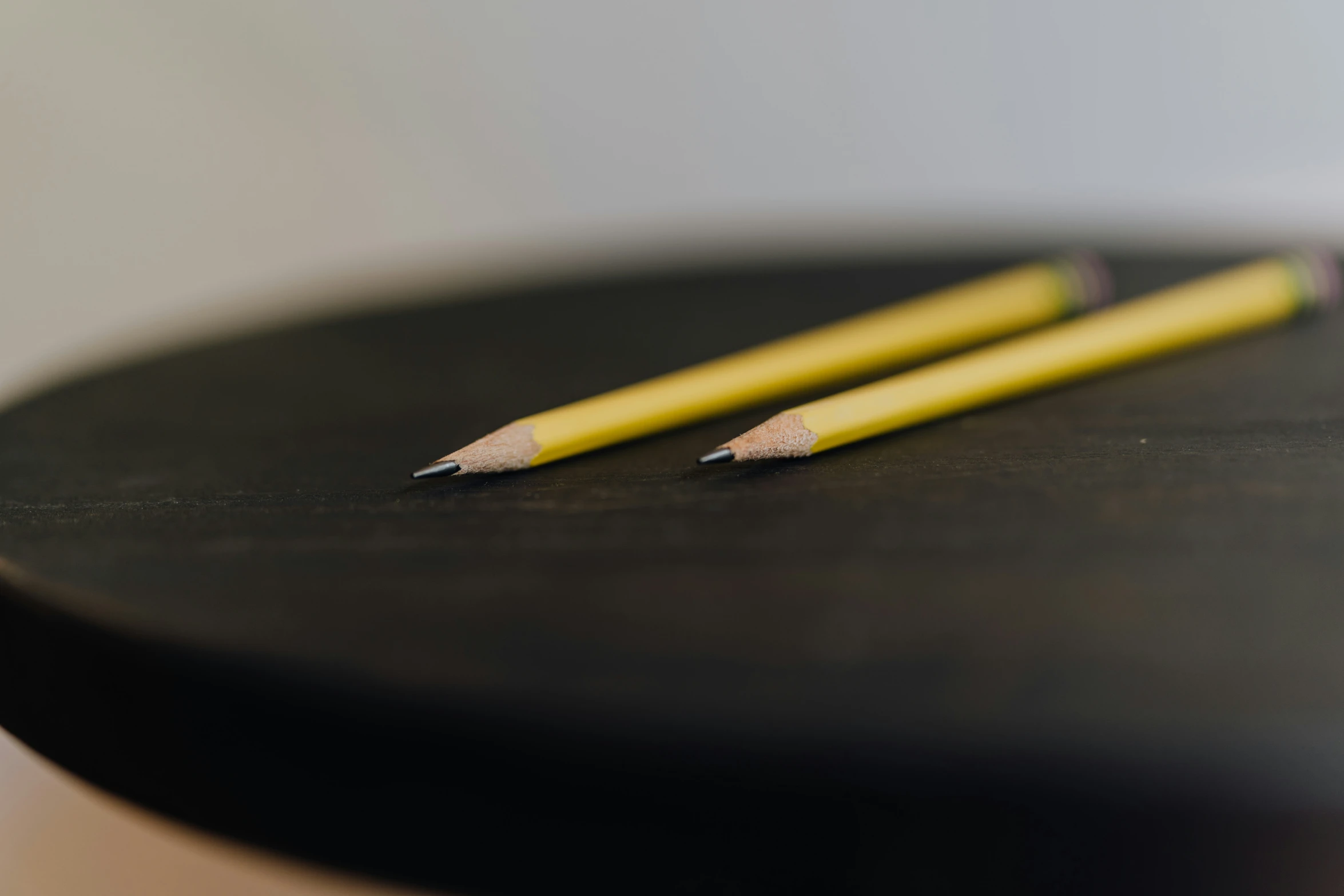 a pair of pencils on a surface with only one end of the yellow