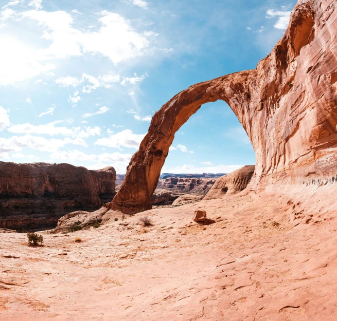 a rock arch in a dirt canyon with a sky background