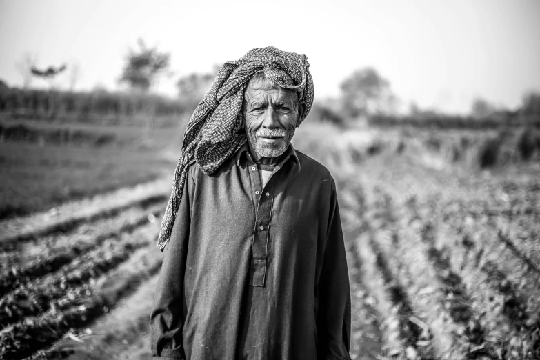 a man standing in a field with a headscarf over his shoulder