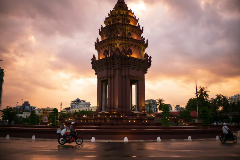 two people riding bicycles near a clock tower