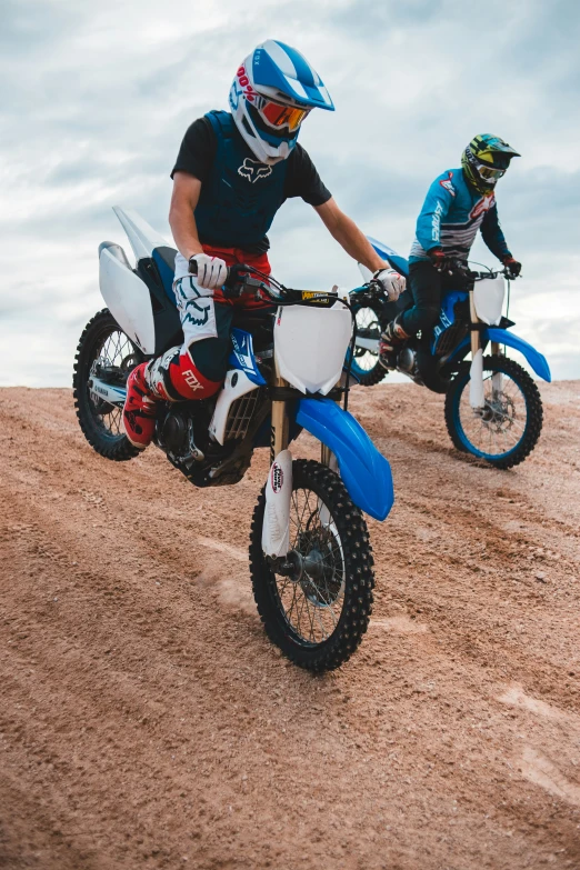 two men on dirt bikes racing uphill