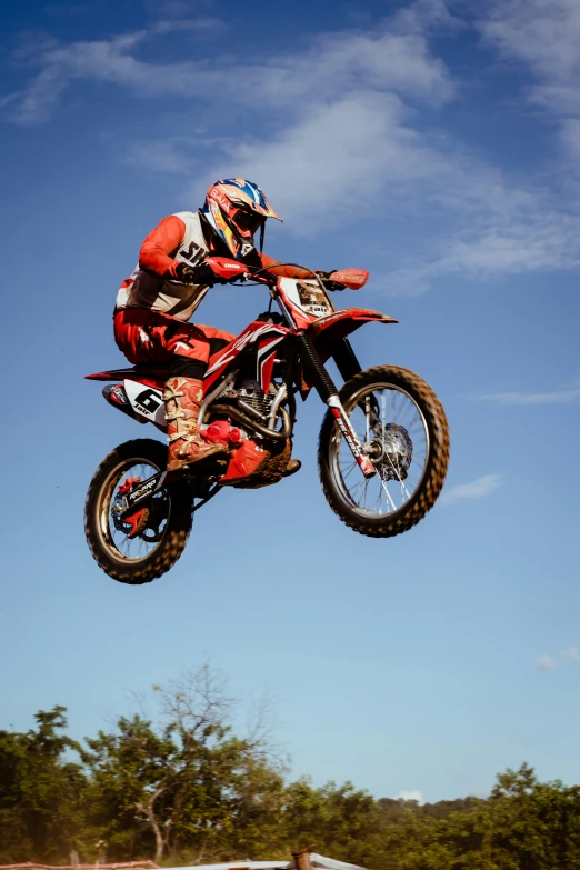 a motorcross biker is in mid air over the dirt