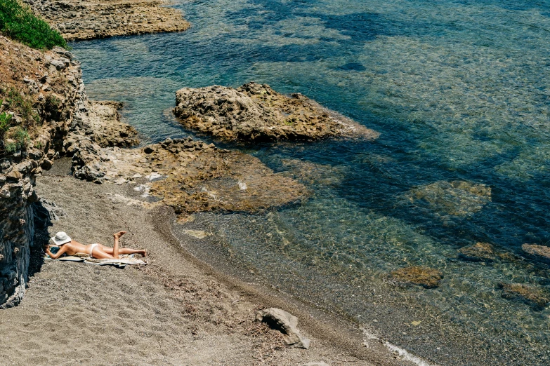 a woman lying on the beach in front of the water