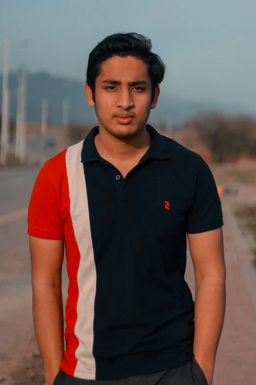 a man in black shirt and gray shorts standing by a paved road