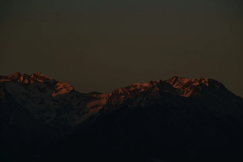 the dark background shows a mountain range that is dotted with brown snow