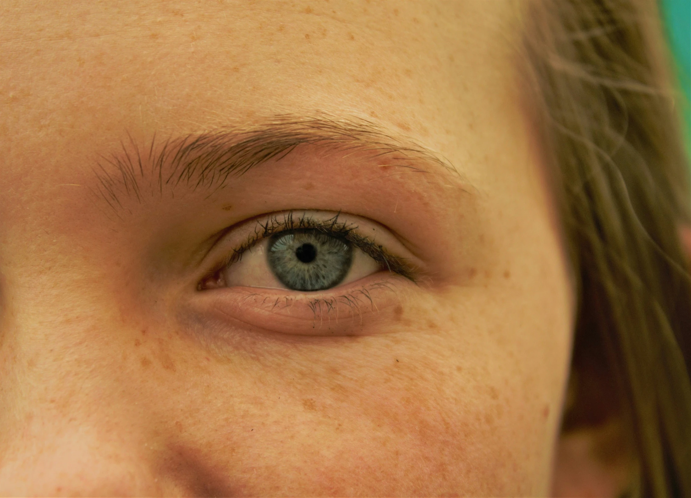 a close up of an eye with long hair and a gray eyeshade