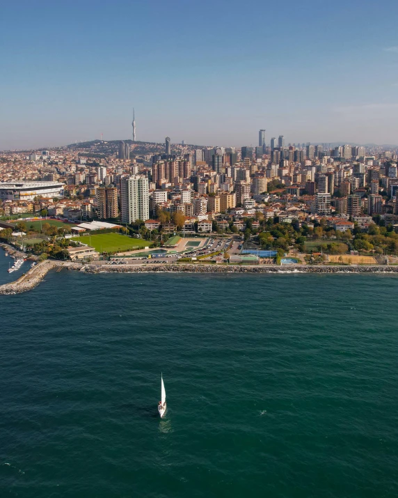 an island with a sail boat and a large city in the background