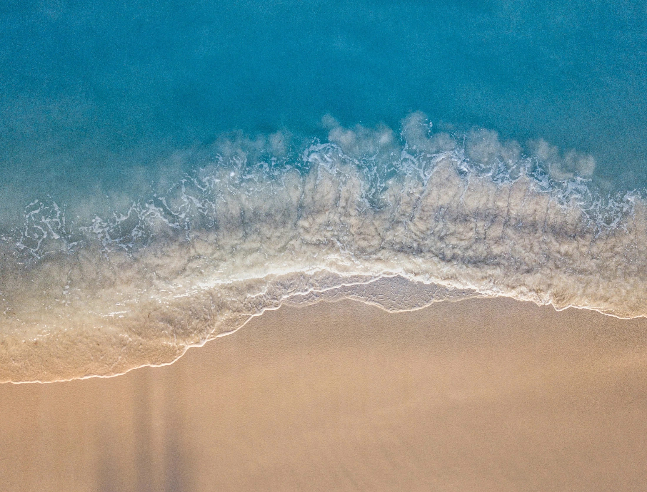 a wave rolls through the sand on a beach